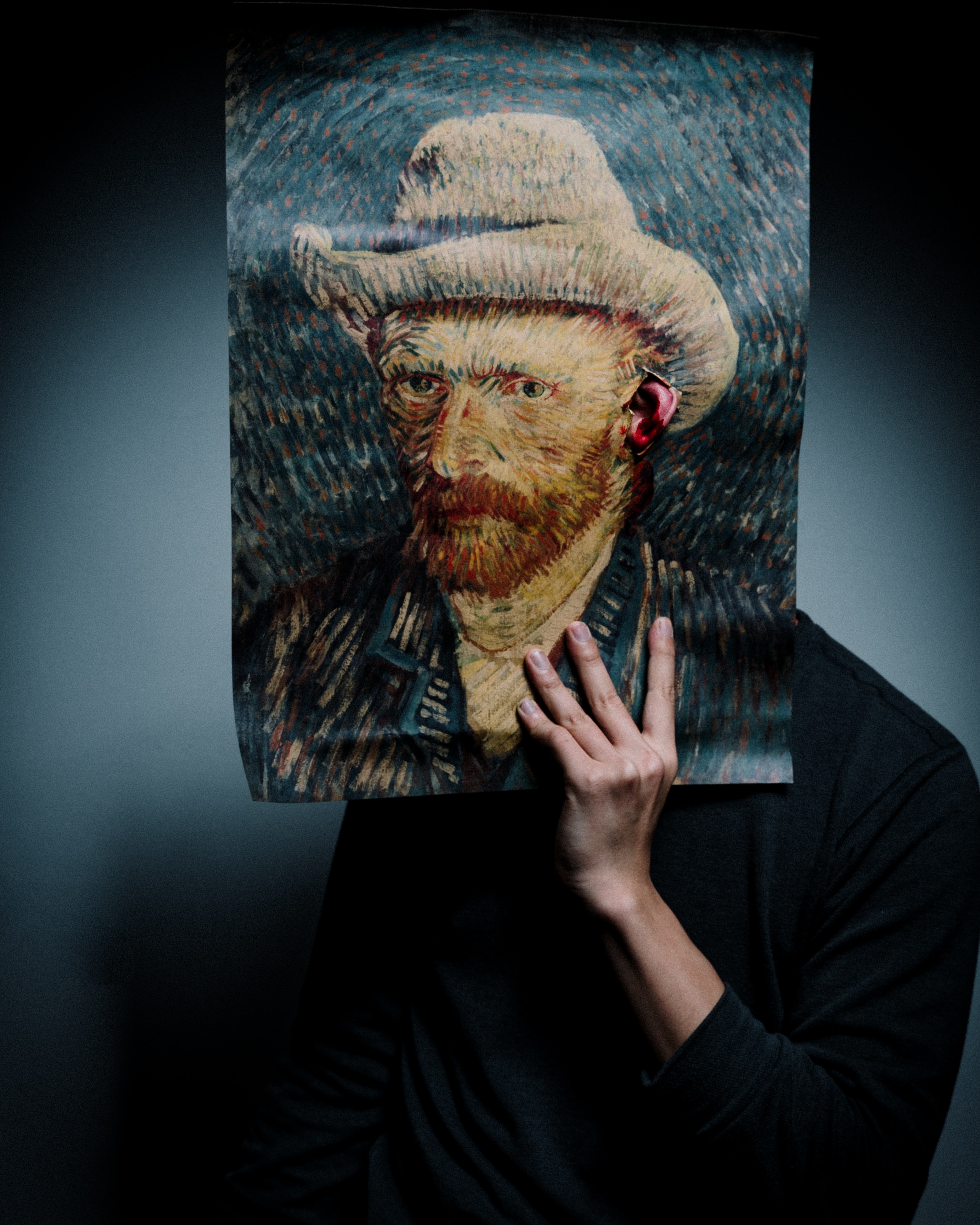 Cilvēks, kas tur van Goga pašportretu priekšā savai sejai